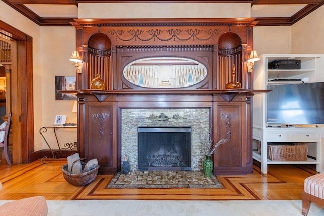 living area featuring a fireplace with flush hearth, crown molding, and baseboards