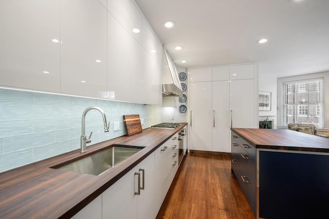 kitchen featuring wood counters, sink, backsplash, dark hardwood / wood-style flooring, and white cabinets