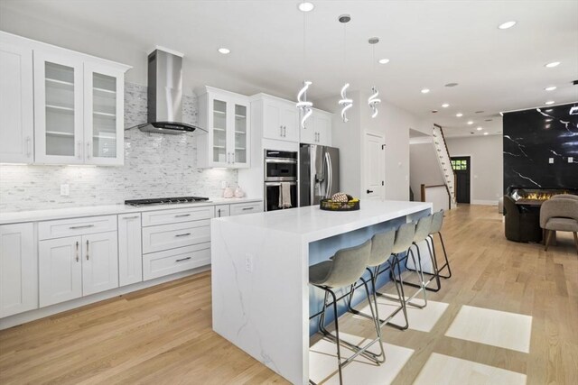 45 Sargent Ave, Somerville, MA 02145 - kitchen featuring wall chimney range hood, appliances with stainless steel finishes, a center island, white cabinets, and decorative backsplash