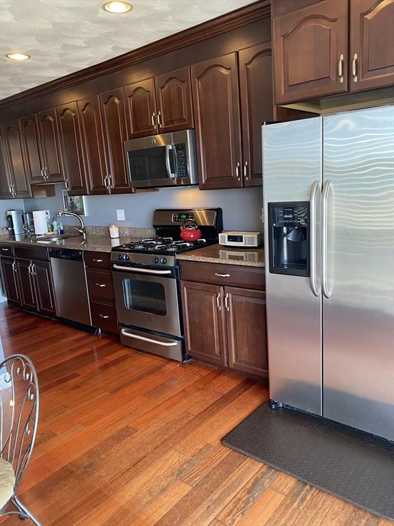 876 Shirley Unit 1, Winthrop, MA 02152 - kitchen with stainless steel appliances, dark wood-type flooring, dark brown cabinets, recessed lighting, and stone countertops