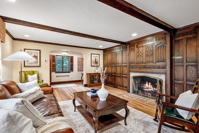 170 Atlantic Ave, Swampscott, MA 01907 - living area with arched walkways, beam ceiling, light wood-style floors, ornamental molding, and a fireplace with flush hearth