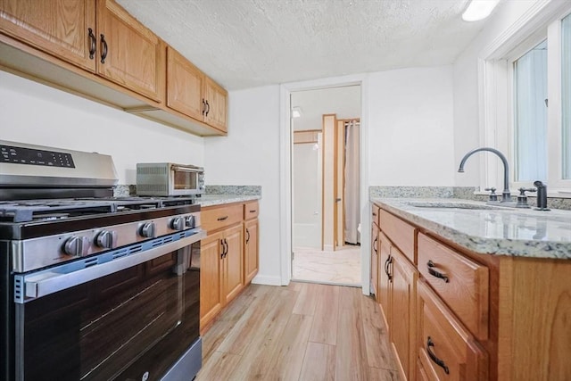 6 Hillside Rd, Holland, MA 01521 - kitchen featuring gas stove, light wood-style floors, a sink, a textured ceiling, and light stone counters