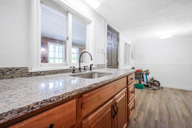 6 Hillside Rd, Holland, MA 01521 - kitchen featuring a sink, light wood-type flooring, light stone counters, brown cabinets, and a wainscoted wall
