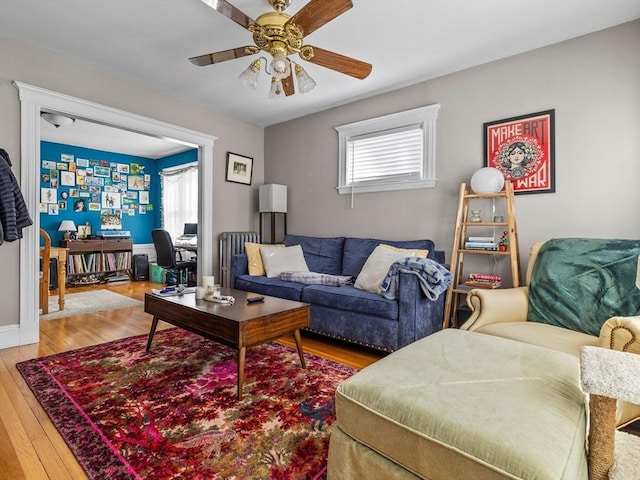 living room featuring hardwood / wood-style floors, a ceiling fan, and baseboards