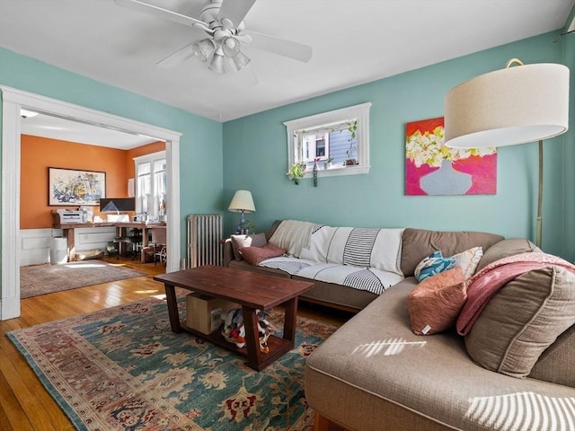 living room featuring hardwood / wood-style floors, radiator heating unit, a wainscoted wall, and ceiling fan