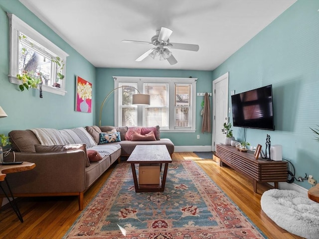 living area featuring baseboards, wood finished floors, and a ceiling fan