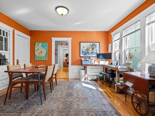 dining space with hardwood / wood-style floors and a wainscoted wall