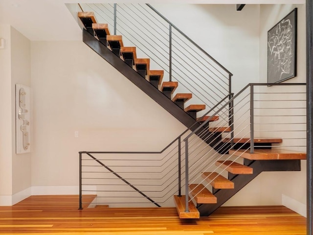 staircase with hardwood / wood-style floors and a towering ceiling