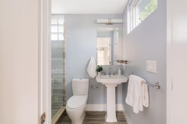 bathroom featuring sink, hardwood / wood-style flooring, a shower with shower door, and toilet