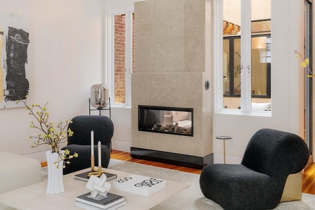 living room featuring wood-type flooring, a fireplace, and a healthy amount of sunlight