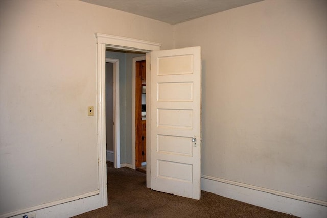 spare room with dark colored carpet