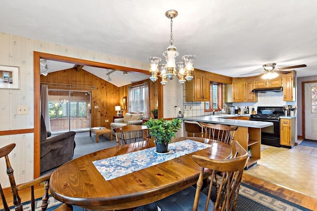 dining area with a chandelier, ceiling fan, and wood walls