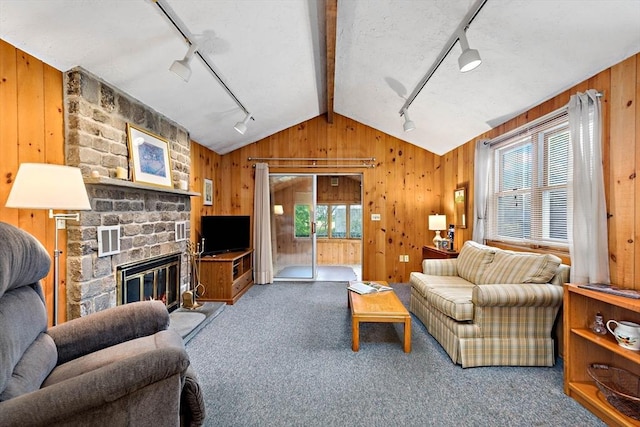 carpeted living area featuring rail lighting, vaulted ceiling, wooden walls, and a fireplace