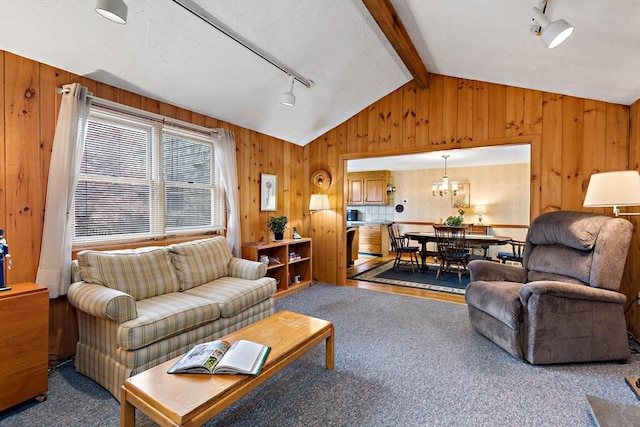 carpeted living room with vaulted ceiling, track lighting, wood walls, and a chandelier