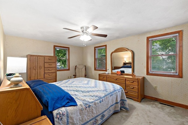bedroom featuring wallpapered walls, light carpet, a ceiling fan, and baseboards