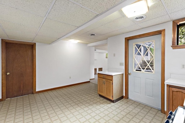 kitchen featuring a paneled ceiling, light countertops, light flooring, baseboards, and range