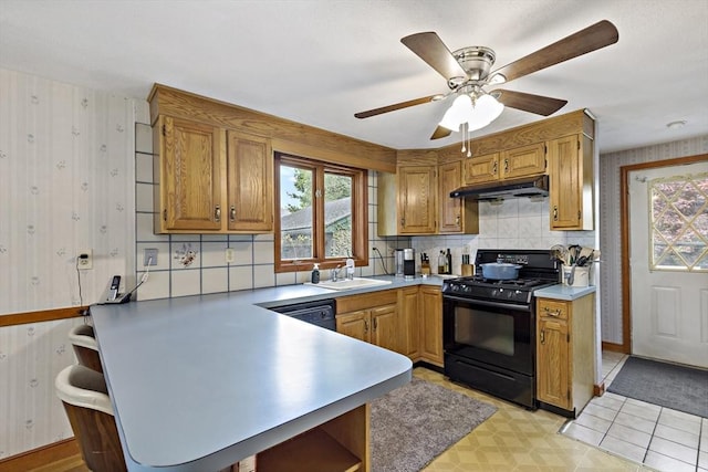 kitchen featuring black appliances, a peninsula, under cabinet range hood, wallpapered walls, and tasteful backsplash