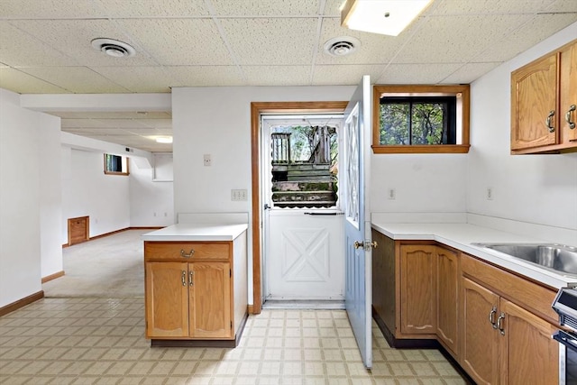 kitchen featuring light countertops, light flooring, a drop ceiling, baseboards, and range