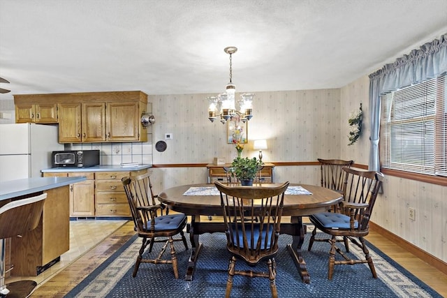 dining room with a chandelier, wooden walls, light wood-type flooring, and wainscoting