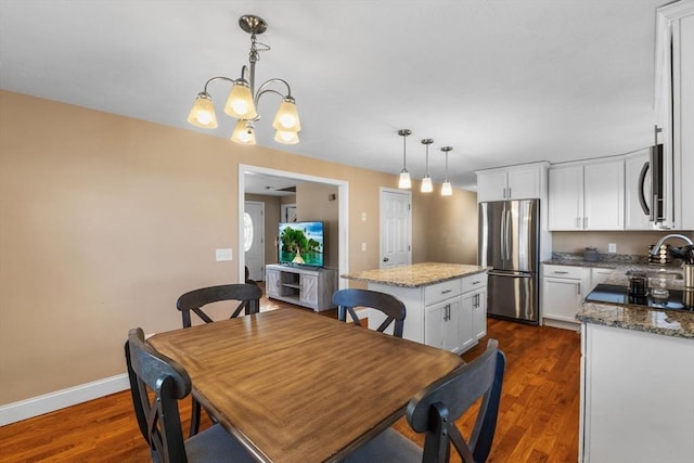 dining room with sink, dark wood-type flooring, and an inviting chandelier