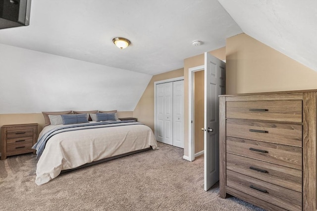 carpeted bedroom with a closet and vaulted ceiling