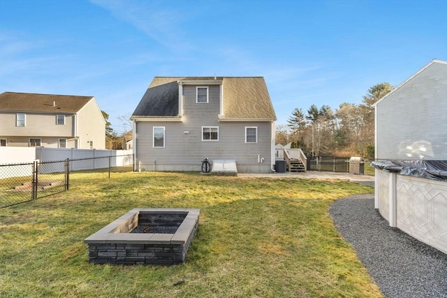 rear view of property featuring a yard and an outdoor fire pit