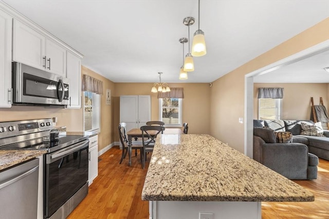 kitchen with white cabinets, decorative light fixtures, a center island, and stainless steel appliances