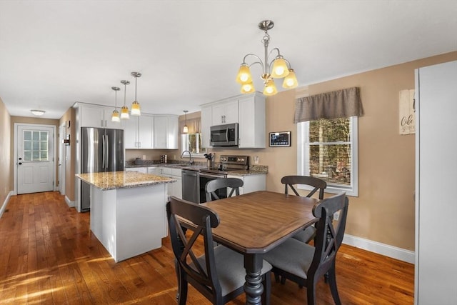 dining room with a notable chandelier, sink, and dark wood-type flooring