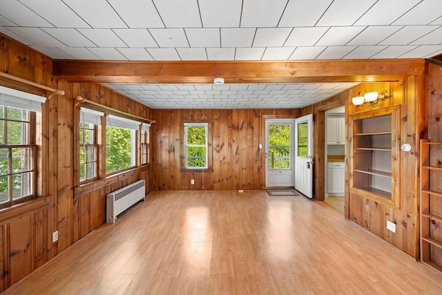 49 Bay View Dr, Shrewsbury, MA 01545 - unfurnished living room with radiator heating unit, light wood-type flooring, wood walls, and beamed ceiling