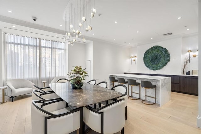 dining room with crown molding and light wood-type flooring