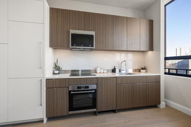 kitchen with sink, light wood-type flooring, and appliances with stainless steel finishes