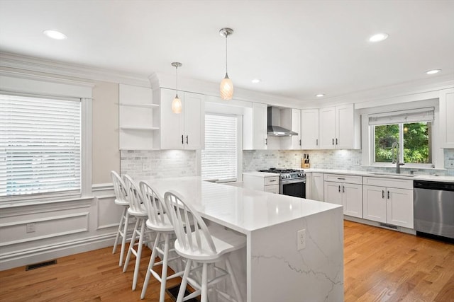 11 Broadway St Unit 2, Stoneham, MA 02180 - kitchen with stainless steel appliances, wall chimney exhaust hood, white cabinetry, a kitchen breakfast bar, and backsplash