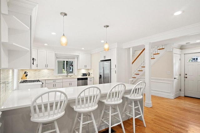 11 Broadway St Unit 2, Stoneham, MA 02180 - kitchen with appliances with stainless steel finishes, a peninsula, tasteful backsplash, ornamental molding, and a kitchen bar