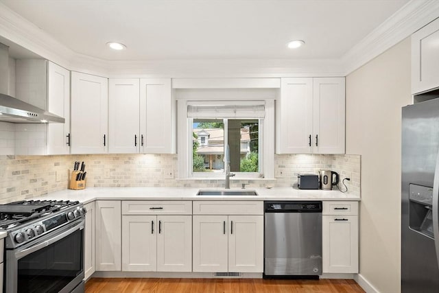 11 Broadway St Unit 2, Stoneham, MA 02180 - kitchen with stainless steel appliances, light countertops, white cabinetry, crown molding, and recessed lighting