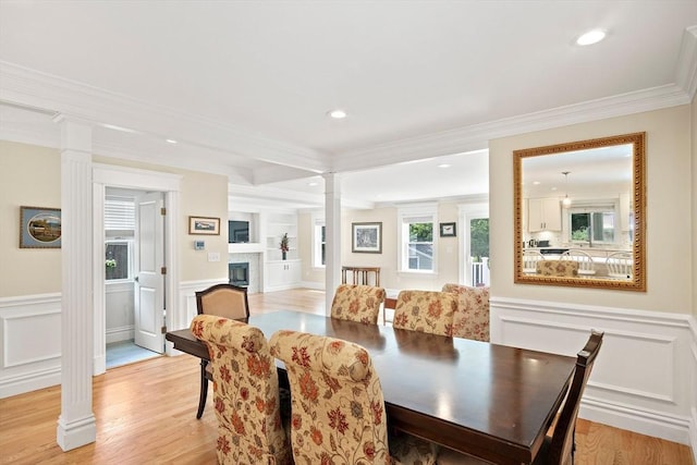 11 Broadway St Unit 2, Stoneham, MA 02180 - dining room featuring ornate columns, crown molding, light wood-style floors, a decorative wall, and a glass covered fireplace