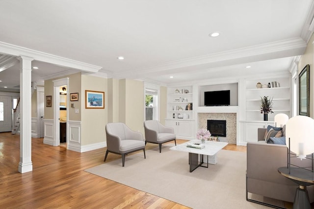11 Broadway St Unit 2, Stoneham, MA 02180 - living area featuring decorative columns, crown molding, light wood finished floors, a brick fireplace, and built in shelves