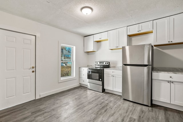 kitchen with a textured ceiling, white cabinets, light hardwood / wood-style flooring, and stainless steel appliances