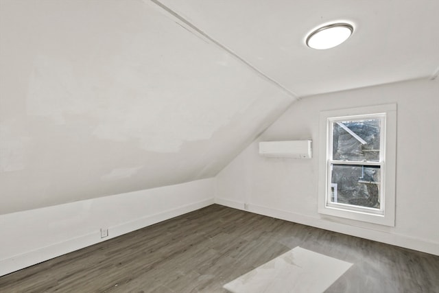 additional living space with dark hardwood / wood-style flooring, lofted ceiling, and a wall mounted air conditioner