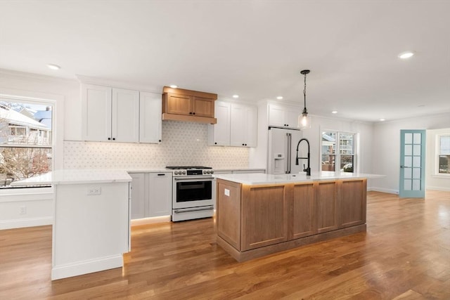 kitchen with a center island with sink, white cabinets, decorative light fixtures, and stainless steel gas range