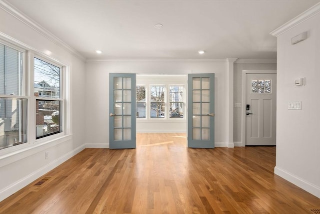 empty room featuring french doors, crown molding, and light hardwood / wood-style floors