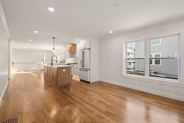 kitchen featuring white cabinetry, a center island with sink, sink, premium appliances, and pendant lighting