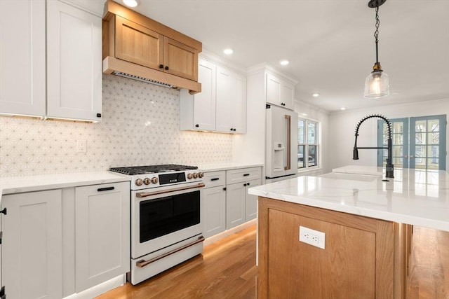 kitchen featuring white appliances, an island with sink, light stone countertops, decorative light fixtures, and white cabinetry