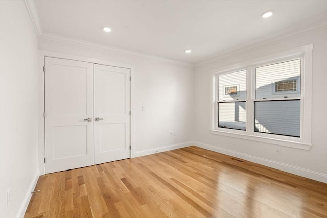 unfurnished bedroom with light hardwood / wood-style floors, crown molding, and a closet