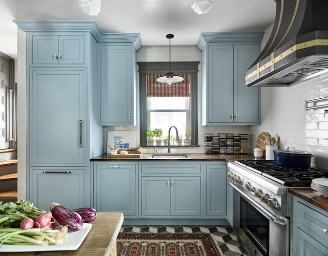 kitchen with wall chimney exhaust hood, high end stainless steel range oven, a sink, dark countertops, and blue cabinetry
