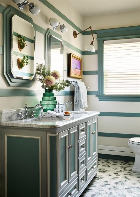 bathroom featuring healthy amount of natural light, toilet, double vanity, and tile patterned floors