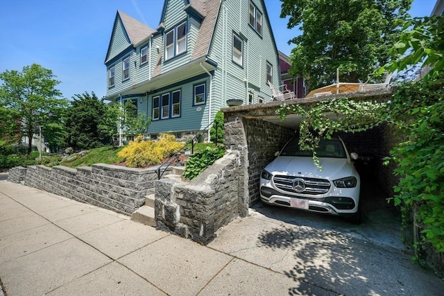 view of side of home with concrete driveway and a carport
