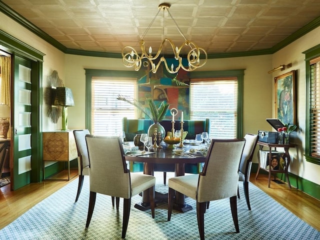 dining room featuring ornamental molding, a chandelier, healthy amount of natural light, an ornate ceiling, and wood finished floors