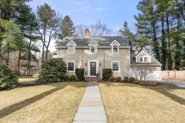 view of front facade with fence, an attached garage, a chimney, a front lawn, and aphalt driveway