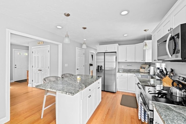 111 Spruce St, Middleboro, MA 02346 - kitchen featuring appliances with stainless steel finishes, a breakfast bar area, white cabinets, a kitchen island, and recessed lighting