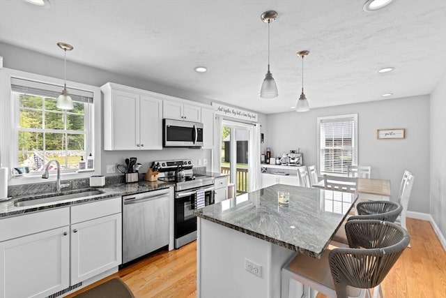111 Spruce St, Middleboro, MA 02346 - kitchen featuring appliances with stainless steel finishes, a sink, light wood-type flooring, white cabinetry, and a kitchen breakfast bar
